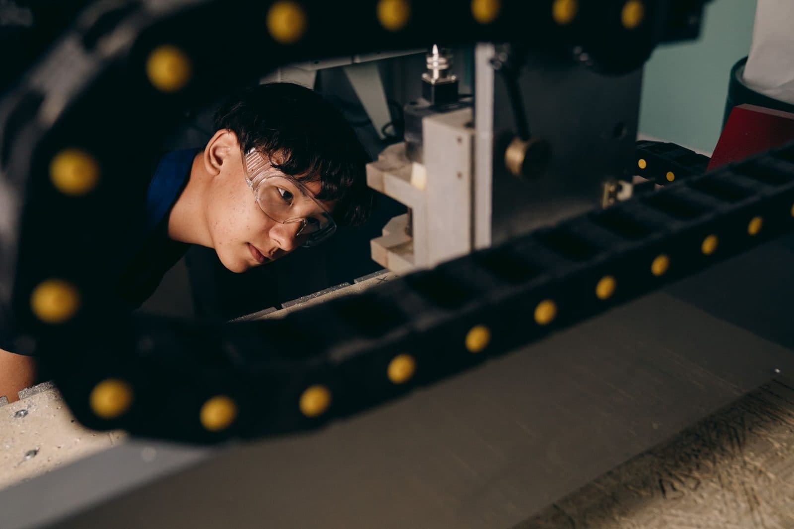 Jeune homme portant des lunettes de protection observant une machine-outil dans un atelier